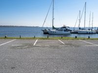 a parking lot with several sailboats docked and a blue sky in the background near the water