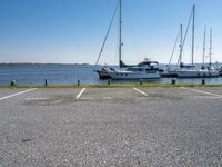 a parking lot with several sailboats docked and a blue sky in the background near the water