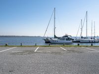 a parking lot with several sailboats docked and a blue sky in the background near the water