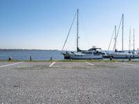 a parking lot with several sailboats docked and a blue sky in the background near the water