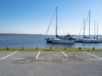 a parking lot with several sailboats docked and a blue sky in the background near the water