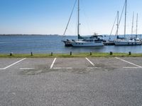 a parking lot with several sailboats docked and a blue sky in the background near the water