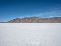 an image of a white open field on a sunny days sky with mountains in the background