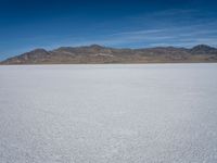 an image of a white open field on a sunny days sky with mountains in the background