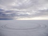 a circle shaped picture with clouds in the background on a desert plain with footprints in the sand