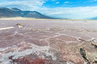 a sandy plain with an unusual sky background and mountains in the background the colors of the mud and the rocks