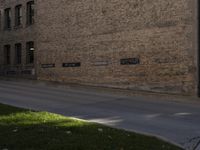 a man riding a bicycle down the middle of a street next to a brick building