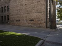 a man riding a bicycle down the middle of a street next to a brick building