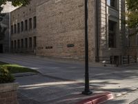 a lamp post on the side of a sidewalk next to a building with many windows