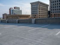 several large empty parking spaces in the city with buildings nearby in front of them -