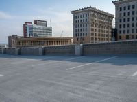 several large empty parking spaces in the city with buildings nearby in front of them -