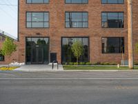 an empty street in front of a large red brick building on the other side of the road is a street light that has a line for motorists