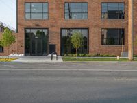 an empty street in front of a large red brick building on the other side of the road is a street light that has a line for motorists