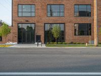 an empty street in front of a large red brick building on the other side of the road is a street light that has a line for motorists