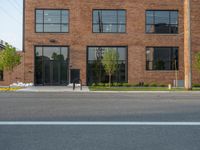 an empty street in front of a large red brick building on the other side of the road is a street light that has a line for motorists