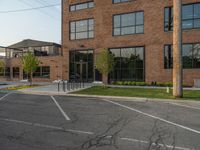 an empty street in front of a large red brick building on the other side of the road is a street light that has a line for motorists