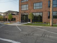 an empty street in front of a large red brick building on the other side of the road is a street light that has a line for motorists