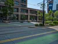 the green paint is painted on a bike path in front of an office building and large, trees