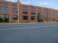 an empty street in front of a large red brick building on the other side of the road is a street light that has a line for motorists