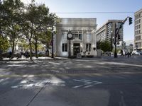 a building with a clock sitting on the corner of a city street with some vehicles and people