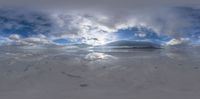 a photo of snow covered ground with clouds and a mountain in the back ground below