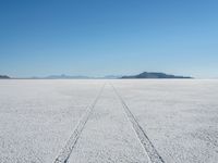 a long track is painted in the middle of a vast empty field with mountains behind it