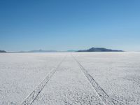 a long track is painted in the middle of a vast empty field with mountains behind it