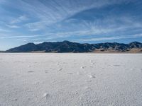 an empty area with a mountain in the distance and some footprints in the sand on it