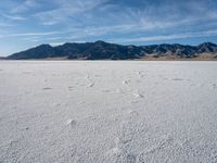 an empty area with a mountain in the distance and some footprints in the sand on it
