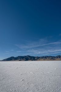 an empty area with a mountain in the distance and some footprints in the sand on it