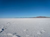 a lone fire hydrant standing alone on a dry land with a mountain in the background