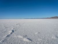 a lone fire hydrant standing alone on a dry land with a mountain in the background