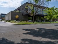 a building with a logo painted on the side near a street that has a sidewalk next to it