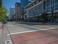 the green paint is painted on a bike path in front of an office building and large, trees