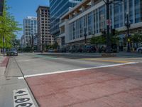 the green paint is painted on a bike path in front of an office building and large, trees