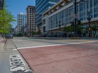 the green paint is painted on a bike path in front of an office building and large, trees