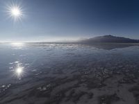 the sun shines above the horizon and water and rock formations along the shore line