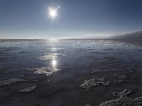 the sun shines above the horizon and water and rock formations along the shore line