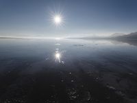 the sun shines above the horizon and water and rock formations along the shore line