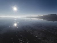 the sun shines above the horizon and water and rock formations along the shore line