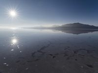 the sun shines above the horizon and water and rock formations along the shore line