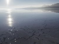 the sun shines above the horizon and water and rock formations along the shore line