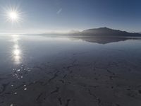 the sun shines above the horizon and water and rock formations along the shore line