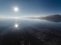 the sun shines above the horizon and water and rock formations along the shore line