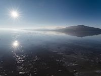 the sun shines above the horizon and water and rock formations along the shore line