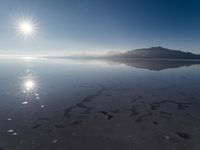 the sun shines above the horizon and water and rock formations along the shore line