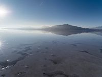 the sun shines above the horizon and water and rock formations along the shore line