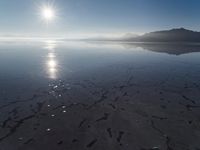 the sun shines above the horizon and water and rock formations along the shore line