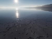 the sun shines above the horizon and water and rock formations along the shore line