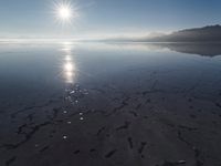 the sun shines above the horizon and water and rock formations along the shore line